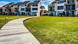 Um edifício residencial moderno de vários andares com um deck de madeira que dá para uma área gramada.