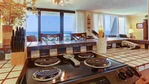Cozinha com fogão, área de refeições e vista para o oceano.