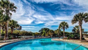 Piscina com indicador de profundidade de 0,9 metros, cercada por palmeiras e cadeiras de sol.