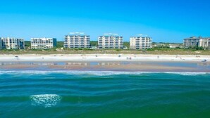 Un hotel frente a la playa con varias construcciones, una playa arenosa y el océano.