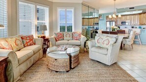 A spacious living room with a sofa, armchairs, a coffee table, and a dining area.