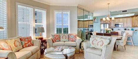 A spacious living room with a sofa, armchairs, a coffee table, and a dining area.