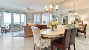 A spacious dining area with a round table, chairs, and a chandelier.