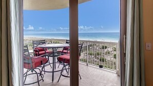 Ein Balkon mit Tisch und Stühlen, mit Blick auf einen Strand.