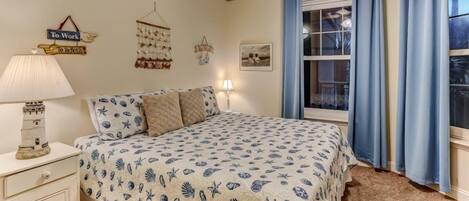 Une chambre à coucher comprenant un lit, une table de chevet, une lampe, une fenêtre avec des rideaux et des éléments de décoration murale.