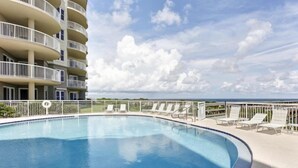 A swimming pool with lounge chairs and a view of a multi-story building. - 42-ocean Place (Fernandina Beach)