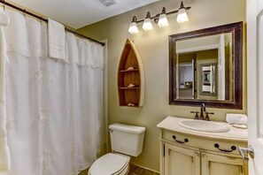 A bathroom with a toilet, sink, and shower curtain. - 42-ocean Place (Fernandina Beach)