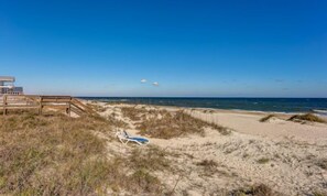 A beach with a wooden boardwalk leading to a sandy area with a lounge chair. - 1060-s-fletcher-ave (Fernandina Beach)