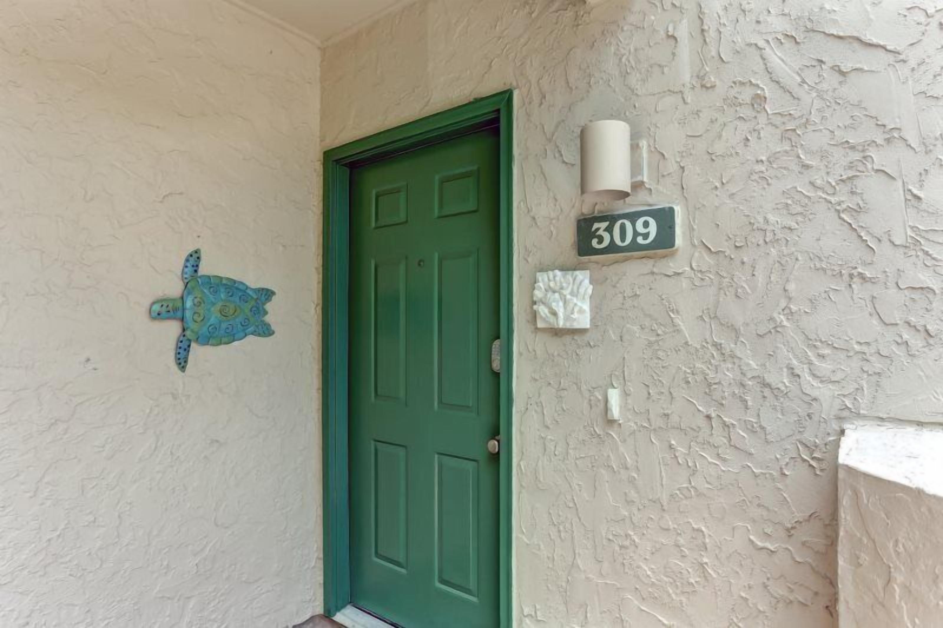 A green door with a number plate '309' and a decorative turtle on the wall.