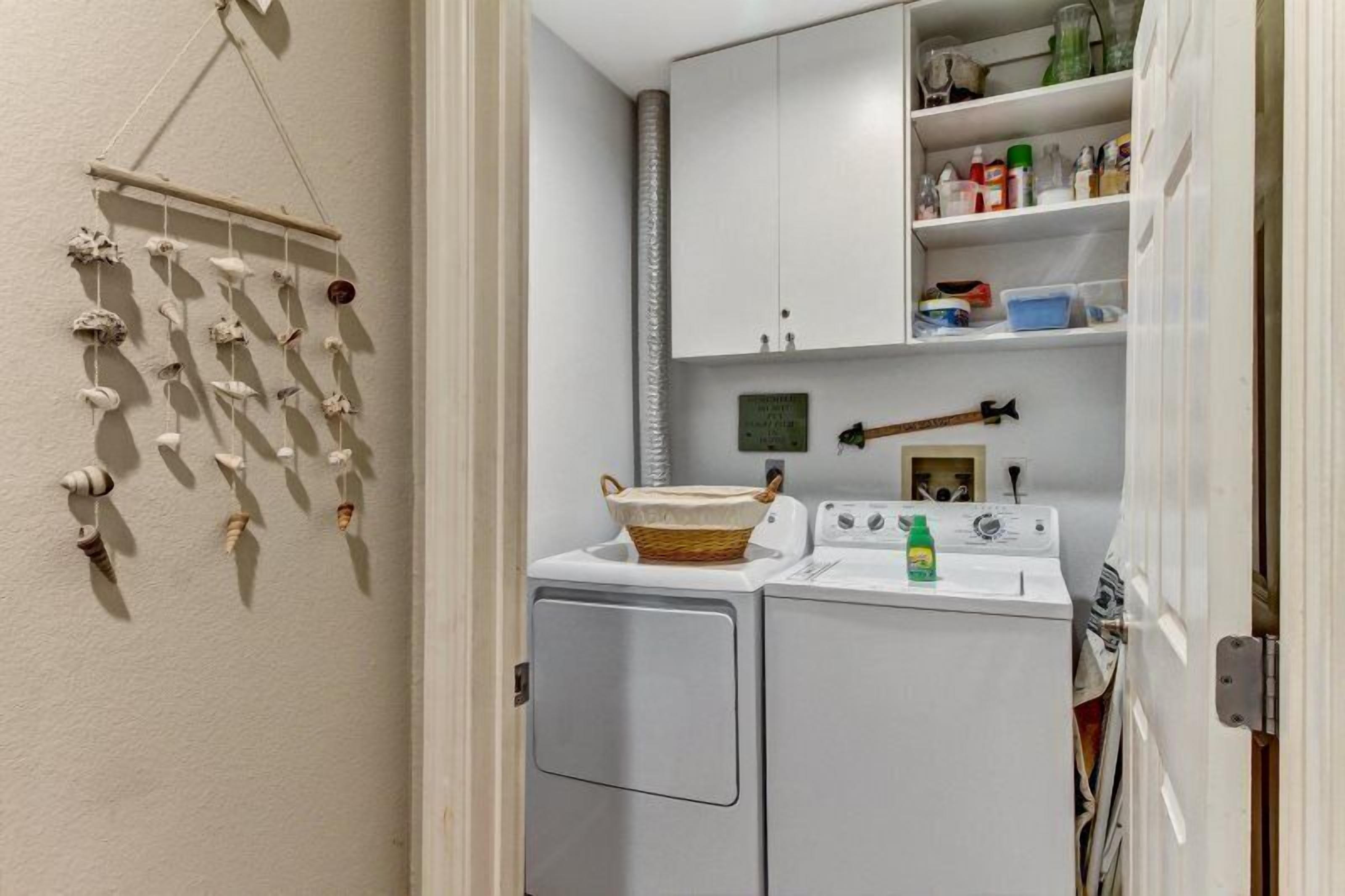 A laundry room with a washing machine, dryer, and shelves with cleaning supplies.