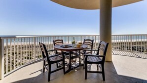A balcony with a round table and four chairs, overlooking a beach. - 25-ocean Place (Fernandina Beach)