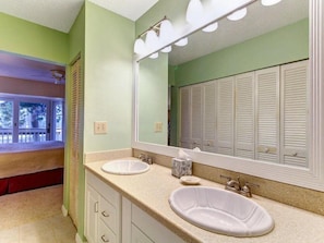 A bathroom with two sinks, a large mirror, and a window with blinds.