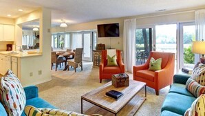 A spacious living area with a sofa, armchairs, a coffee table, and a dining area with chairs and a table. - 2098-beachwood (Fernandina Beach)