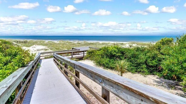 A wooden boardwalk leading to a beach with a clear view of the ocean and sky. - 2098-beachwood (Fernandina Beach)