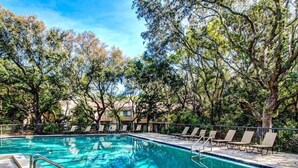 A rectangular swimming pool with a tiled deck, surrounded by trees and lounge chairs. - 2098-beachwood (Fernandina Beach)