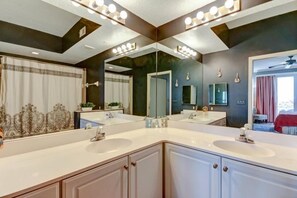 A bathroom with two sinks, a large mirror, and a ceiling light fixture.