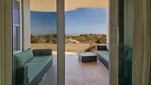 Ein Zimmer mit Blick auf Strand und Dünen, ausgestattet mit einer Couch und einem kleinen Tisch.