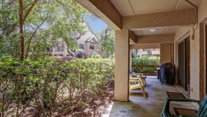 A covered patio area with a view of surrounding houses, a barbecue grill, and outdoor furniture. - 503-sailmaker (Fernandina Beach)