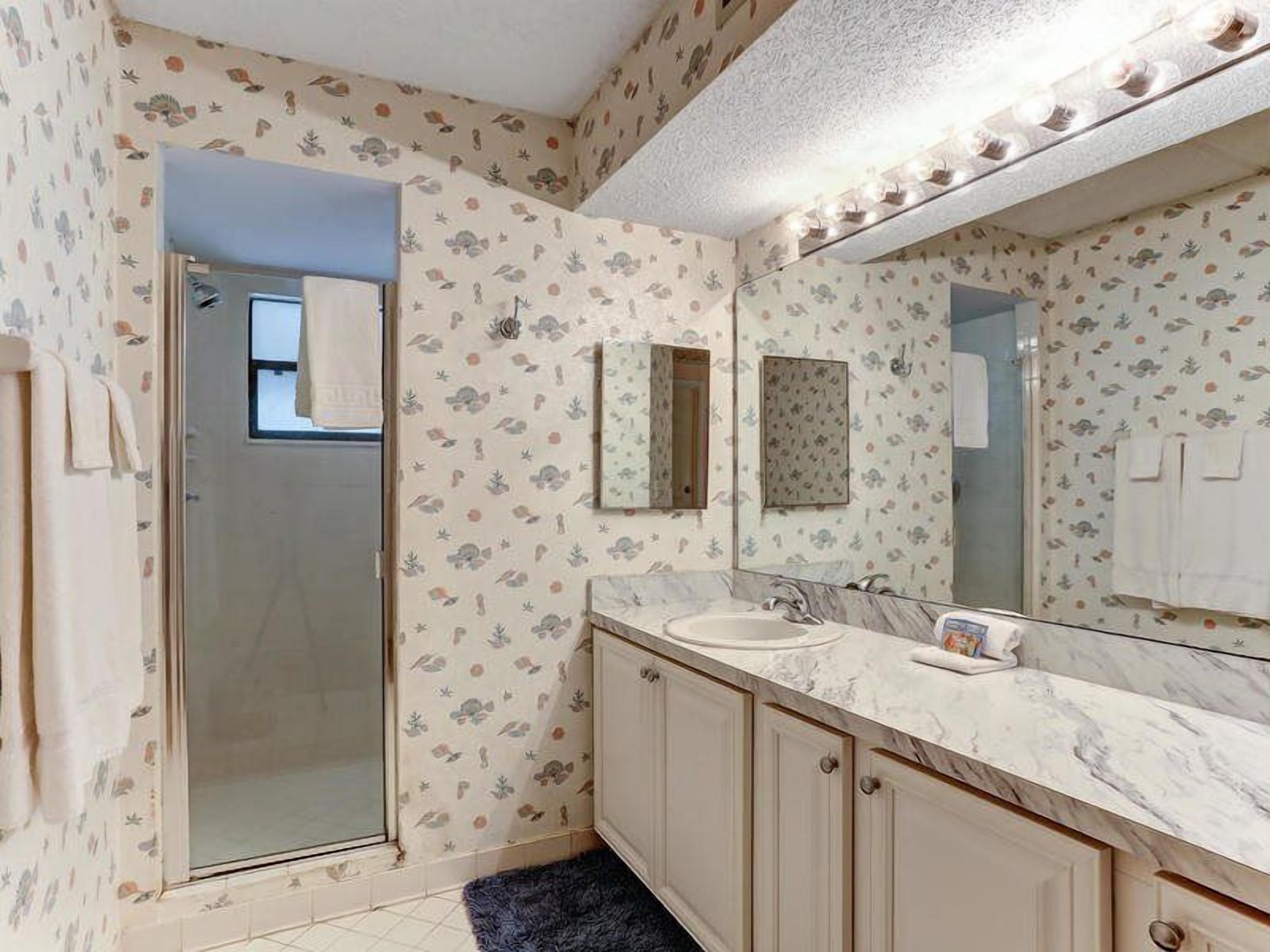 A bathroom with a shower, a sink, and a mirror with lights.