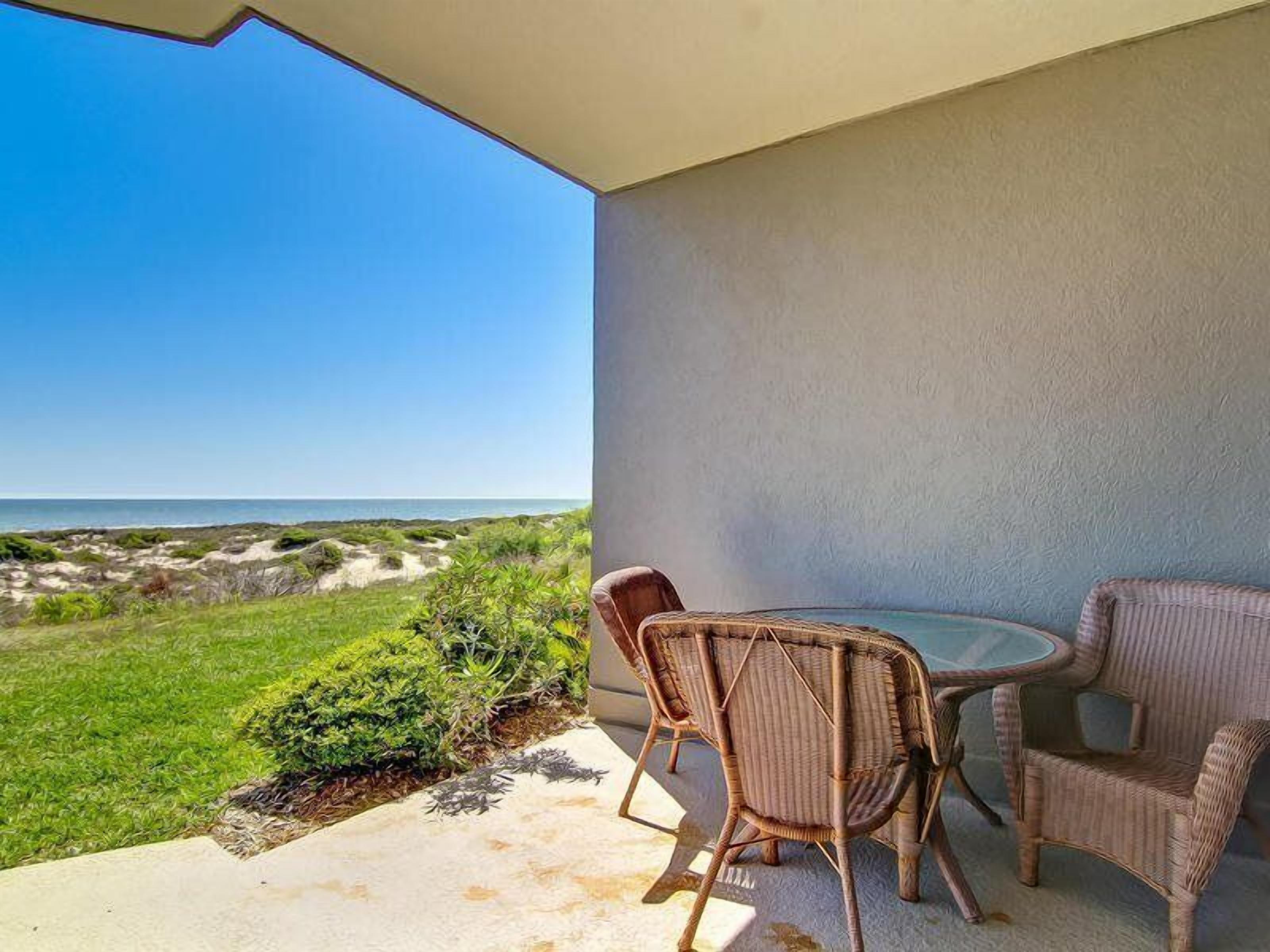 A balcony with wicker furniture and a view of the beach.