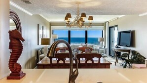 Una cocina moderna con una isla grande, una araña y vista al océano.