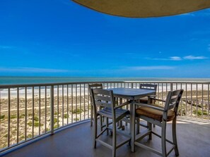 A balcony with a table and chairs overlooking a beach. - 29-ocean-place (Fernandina Beach)