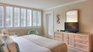 A bedroom with a bed, a dresser, a television, and a window with blinds. - 1141 Beachwalker (Fernandina Beach)