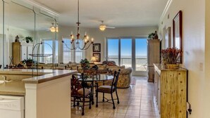 A spacious kitchen with a dining area, large windows, and a chandelier. - 57-ocean-place (Fernandina Beach)