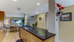 A modern kitchen with a granite countertop, wooden cabinets, and a dining area with a table and chairs.