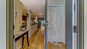 A hallway with a wooden floor leading to a kitchen area with a dining table and chairs.