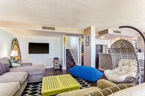 A modern living room with a sofa, a hanging chair, and a flat-screen TV. - 1179-beach-walker (Fernandina Beach)