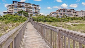 A wooden boardwalk leading to a beachfront hotel with multiple balconies and a clear view of the ocean. - 234-sandcastles (Fernandina Beach)