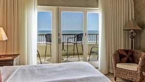 A hotel room with a bed, a chair, a lamp, and a balcony with a view of the sea. - 234-sandcastles (Fernandina Beach)