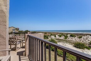 A balcony with a view of the beach, wooden chairs, and a railing. - 712-sailmaker (Fernandina Beach)
