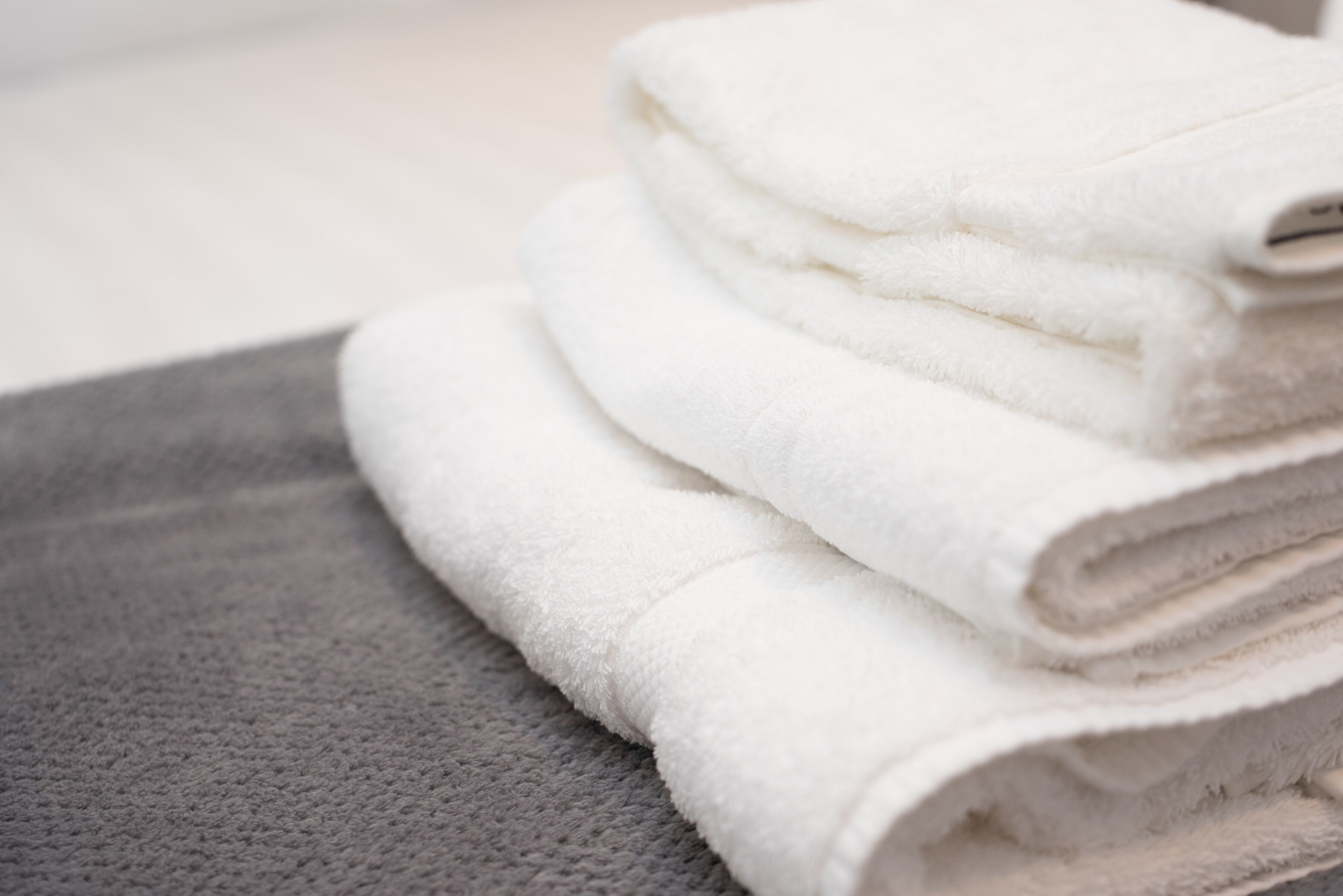 A stack of white towels on a textured grey surface.