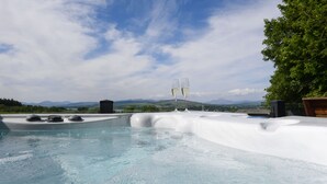 Un bain à remous avec deux coupes de champagne, entouré d’un paysage magnifique composé de montagnes et d’arbres.