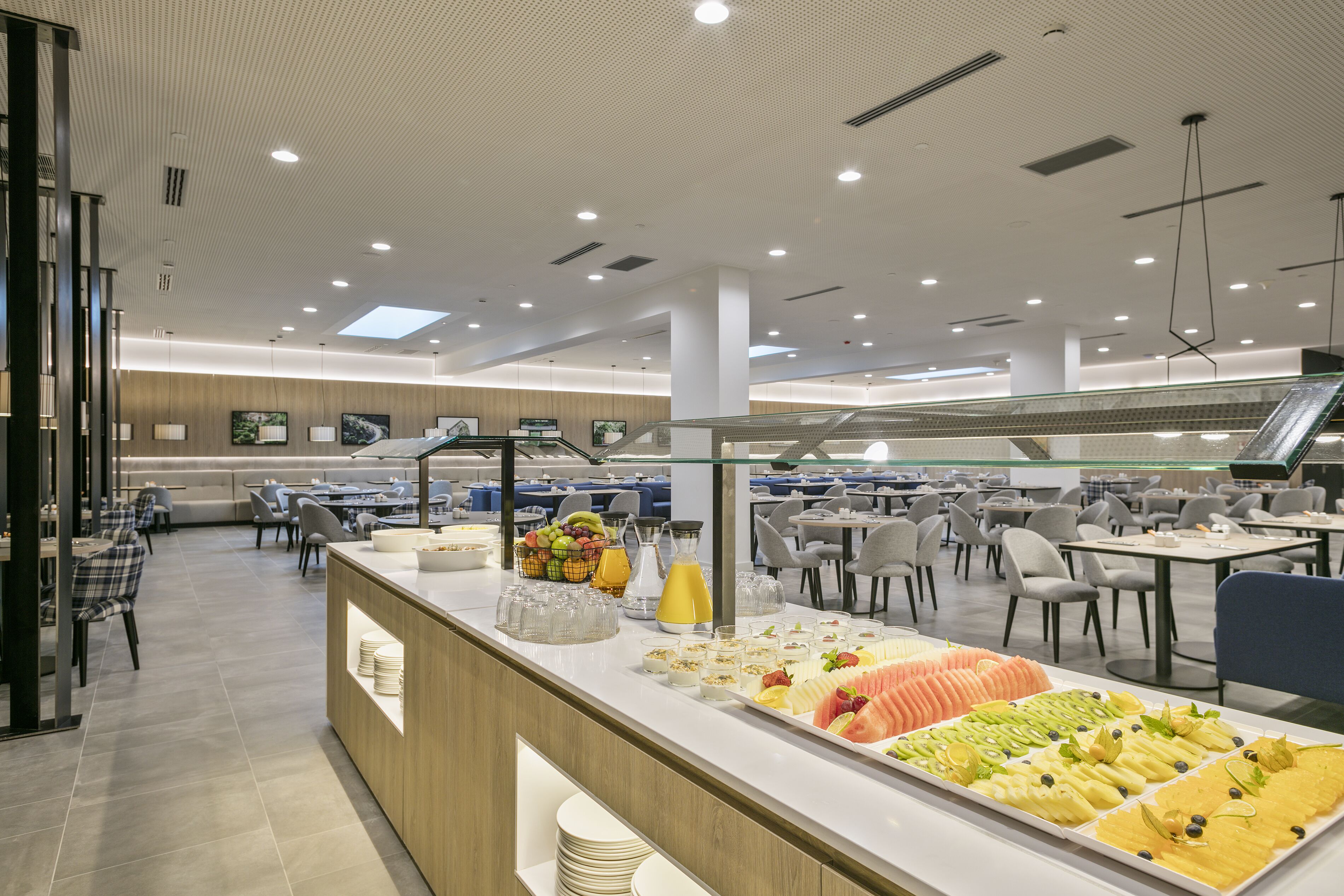 Un comedor moderno con una barra de buffet, que incluye una variedad de frutas y bebidas.