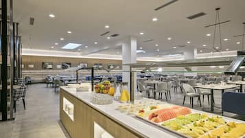 Un comedor moderno con una barra de buffet, que incluye una variedad de frutas y bebidas.