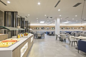 A modern cafeteria with a buffet area, multiple seating tables, and a clean, contemporary design.