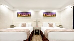 A hotel room with two beds, each with a headboard, a small table with a vase, and two wall-mounted paintings. - The Palms (Hollywood)