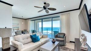 A modern living room with a sofa, armchair, and coffee table, a ceiling fan, and a view of the ocean. - Simply Spectacular 5th Floor Ocean View (Jacó)