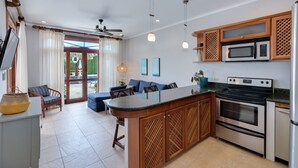 A modern kitchen with a central island, built-in microwave, oven, and refrigerator. - Ground Floor Unit in Beautiful Beachfront Complex (Jacó)