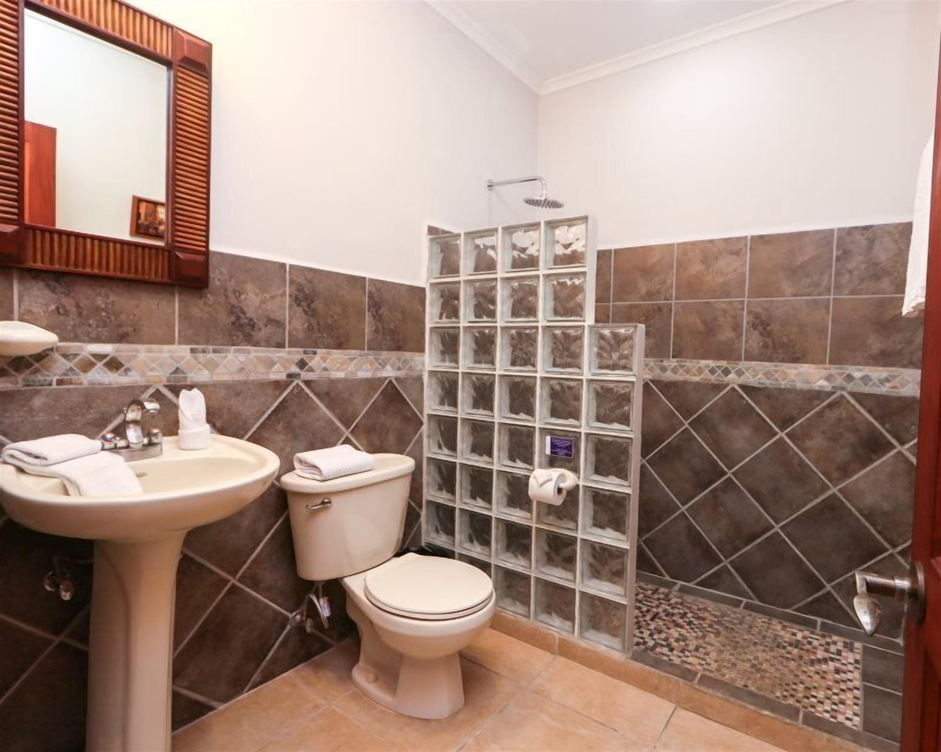 Une salle de bain comprenant un lavabo, des toilettes et un espace douche.