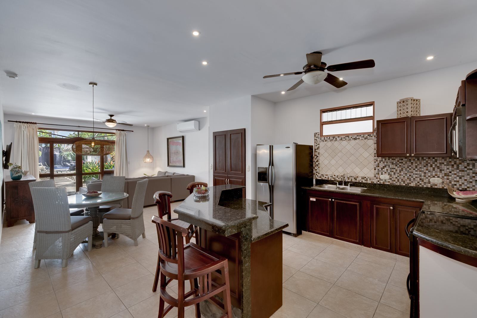 A modern kitchen with a central island, dark wooden cabinets, and a tiled backsplash.