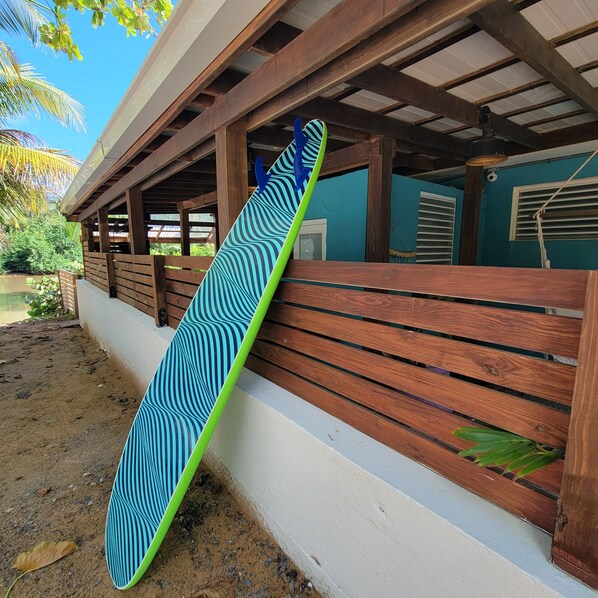 A wooden structure with a green and blue patterned surfboard leaning against it. - Casa Coral - Hostel (Luquillo)