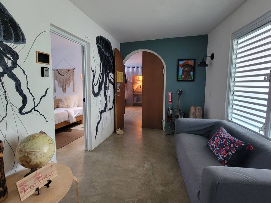 A living room with a grey sofa, a globe, and a wooden sign.