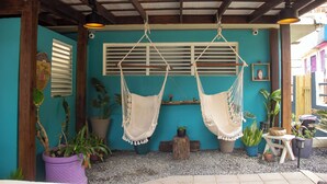 Un espacio al aire libre cubierto con dos hamacas colgantes, plantas en macetas y una estructura de madera.