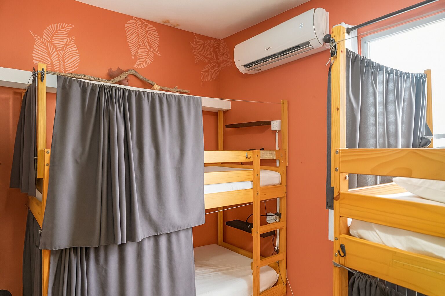 Un dormitorio con literas, un equipo de aire acondicionado y una ventana con cortinas.