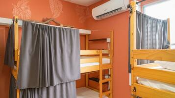 Un dormitorio con literas, un equipo de aire acondicionado y una ventana con cortinas.