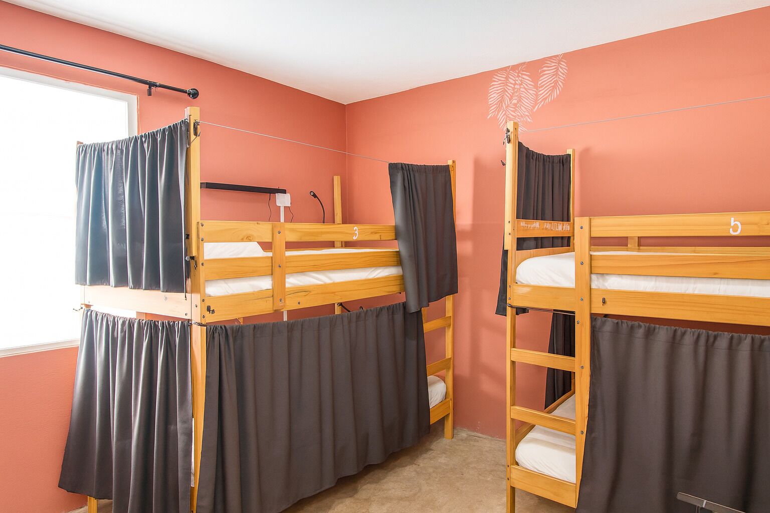 Une chambre de dortoir avec des lits superposés, une fenêtre et une tringle à rideaux.